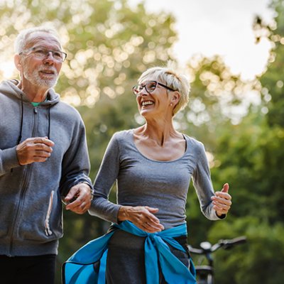 Older couple smiling and jogging. Adobe